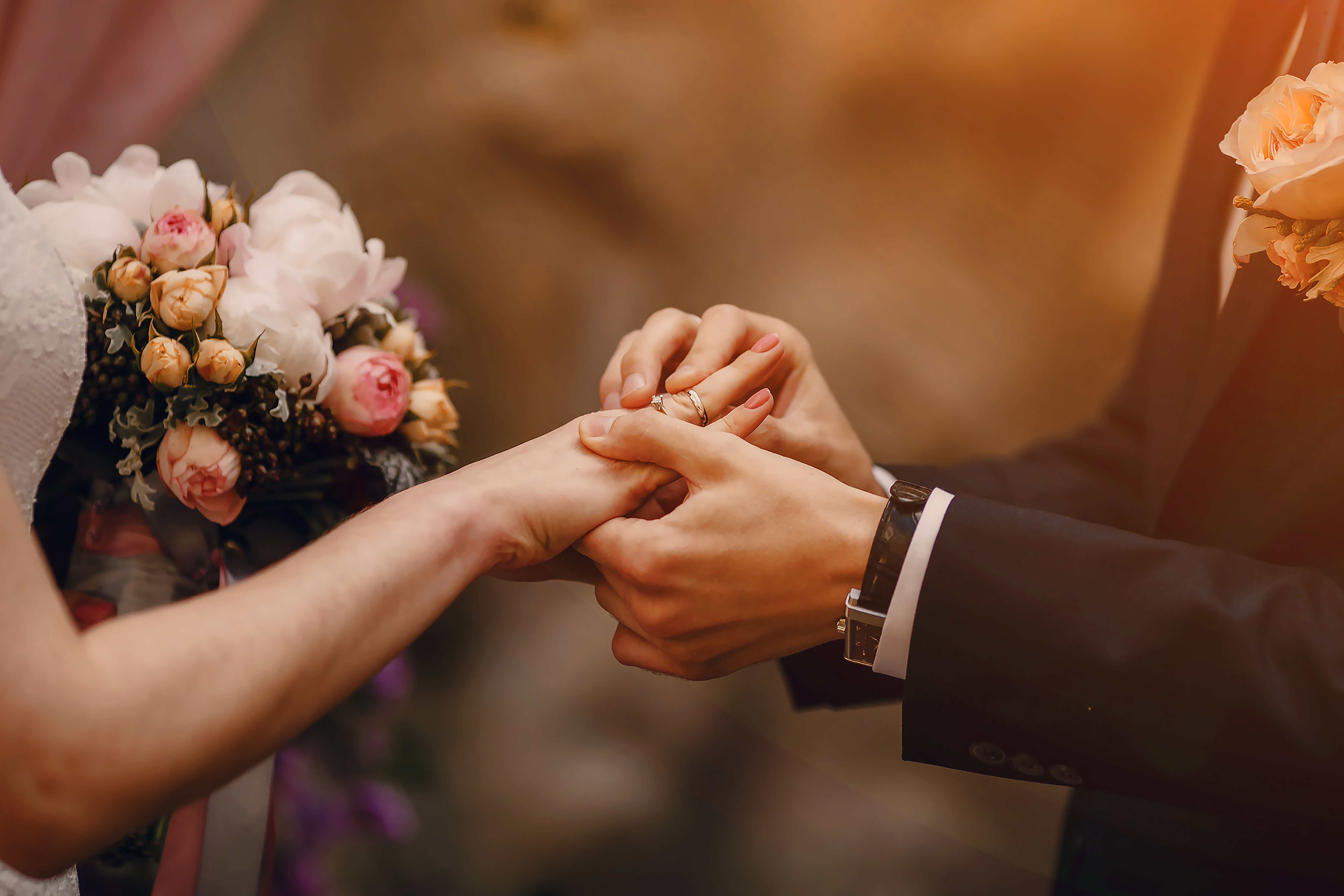 Photo of a groom placing the wedding band onto his wife