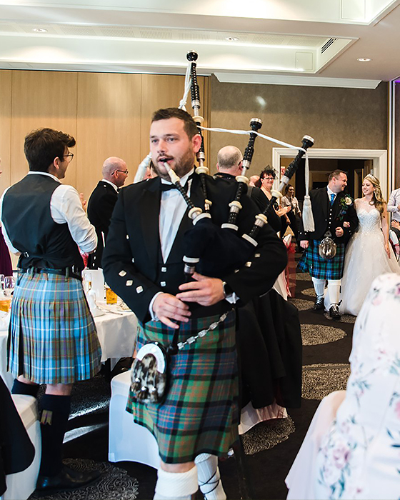 Photo of the loch ness piper leading a bride and groom into their wedding breakfast