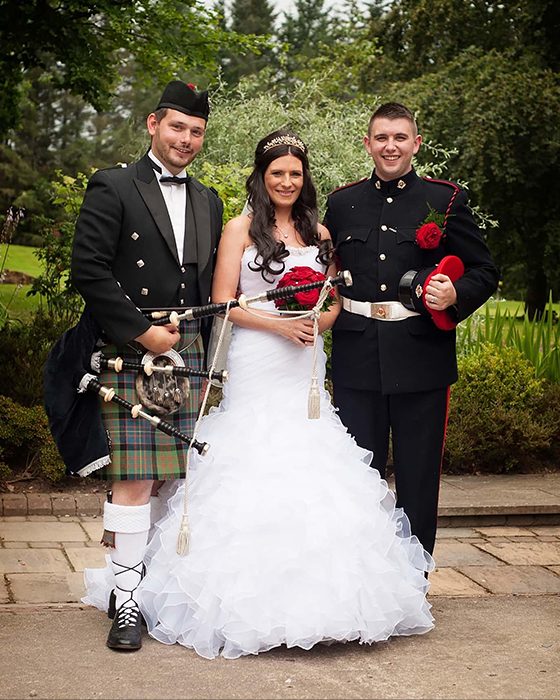 Photo of a bride and groom standing with the loch ness piper