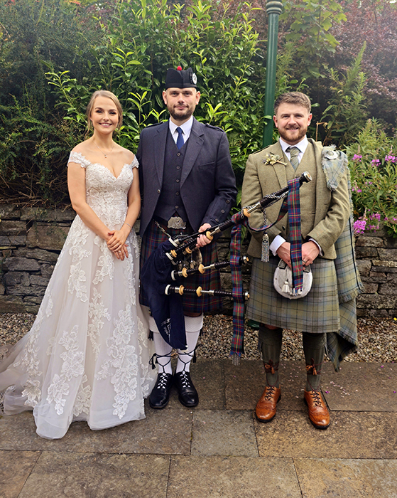 Photo of a bride and groom standing with the loch ness piper