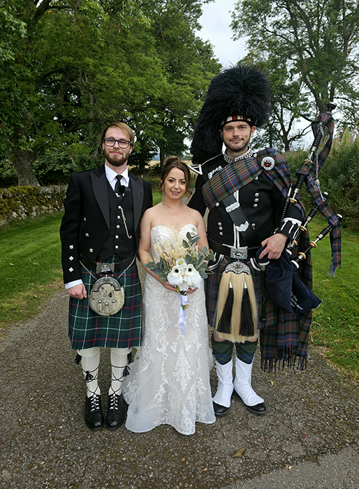 Photo of a bride and groom standing with the loch ness piper