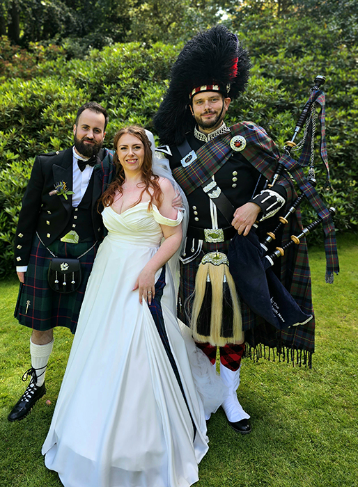 Photo of a bride and groom standing with the loch ness piper